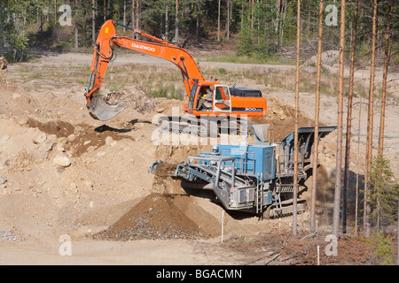 Daewoo digger il caricamento di sabbia e pietre per il rock crusher / macchina del separatore in corrispondenza di una buca di sabbia , Finlandia Foto Stock