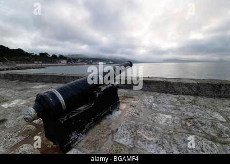 Il cannone sulla parete del porto allo spuntar del giorno a Lyme Regis Foto Stock