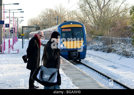 Pendolari su una coperta di neve ferroviario della piattaforma come un treno arriva in.. Foto di Gordon Scammell Foto Stock