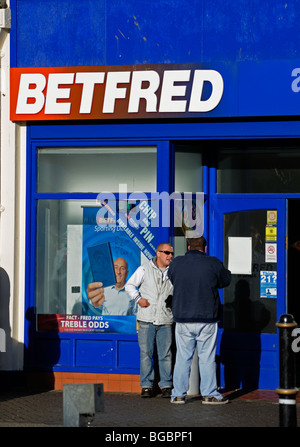 Due uomini al di fuori di un "betfred' negozio di scommesse in Widnes,l'Inghilterra, Regno Unito Foto Stock