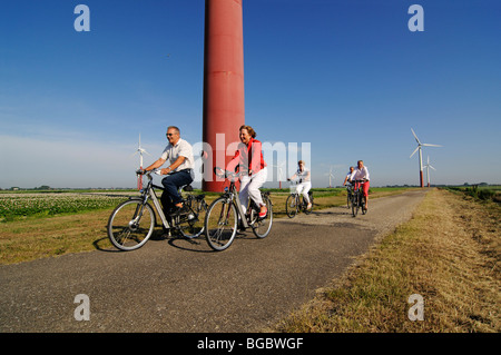 I ciclisti nella parte anteriore delle turbine eoliche, Sexbierum, Friesia, Holland, Paesi Bassi, Europa Foto Stock