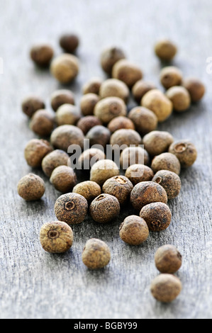 Asciugare diversi grani di pepe della Giamaica in background in legno Foto Stock