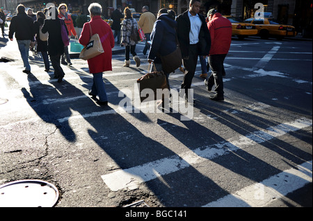 Gli acquirenti di Natale gettano lunghe ombre mentre camminano lungo la Fifth Avenue Midtown Manhattan New York Stati Uniti d' America - Foto Stock