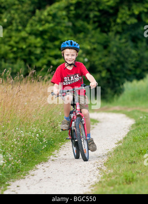 Un ragazzo, 7 anni, in sella ad una bicicletta su una strada sterrata Foto Stock