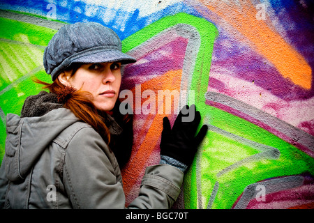 Donna appoggiata contro graffiti-parete coperta Foto Stock