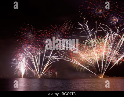 Fuochi d'artificio di esplodere per l'acqua, con lo skyline di Doha, Qatar, appena visibile in background. Foto Stock