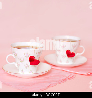 Due tazze con cuori sullo sfondo rosa Foto Stock