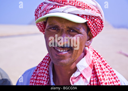 Una chiusura di un egiziano cammello maschio autista che offre corse di cammelli presso le Piramidi di Giza in Egitto Foto Stock
