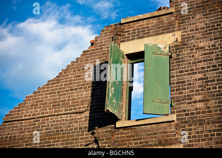 Inquadratura concettuale di un edificio demolito. Parete singola rimane con una finestra in essa, il cielo blu e nuvole bianche. Foto Stock