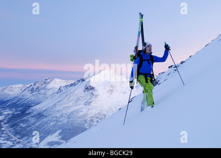 Rosa tenue e blu artico luce midwinter vicino a mezzogiorno, sciatore salendo Andersdalstinden montagna vicino a Tromsoe, Norvegia settentrionale Foto Stock