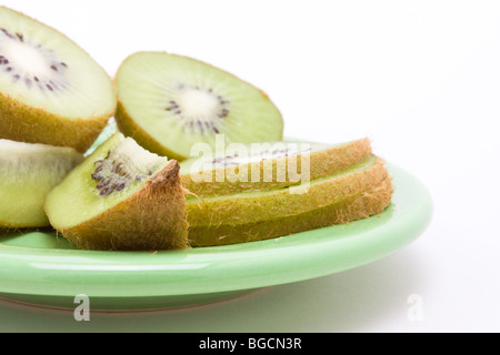 Fresche e mature Kiwi sulla piastra verde isolata contro uno sfondo bianco. Foto Stock