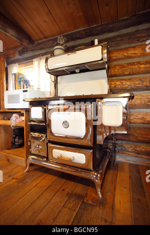 Antica stufa in cucina di un rustico log cabin Foto Stock