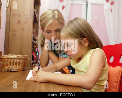 Mom insegnare la sua piccola figlia iscritto nel libro di esercizio Foto Stock