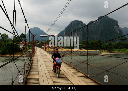 Laos; Vang Vieng; Mororcycle attraversando il ponte su il Nam Song River Foto Stock