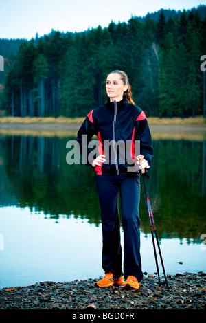 Giovane donna avente una pausa durante una passeggiata accanto a un lago Foto Stock