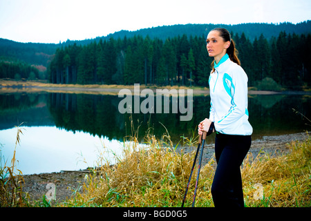 Giovane donna avente una pausa durante una passeggiata accanto a un lago Foto Stock