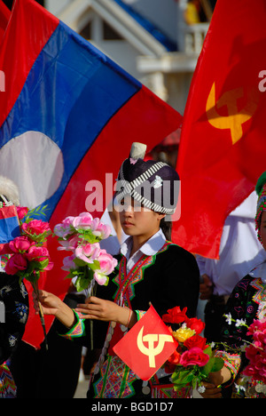 Festival, ragazza Hmong, vestiti in abiti tradizionali, tenendo le bandiere rosse del Partito comunista, bandiera nazionale del Laos, Xam Neu Foto Stock