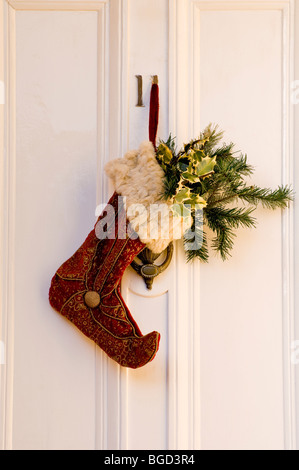 Bella dettagliata e una texture ricca Calza di Natale e Holly su un Regency English Cotswold Town House porta. Foto Stock