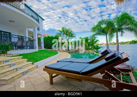 Sedie a sdraio in piscina a waterfront mansion Foto Stock