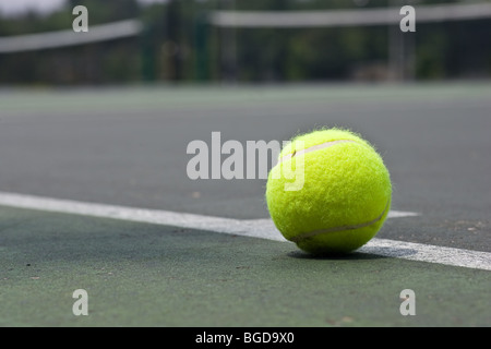 Un primo piano di un giallo palla da tennis appena al di fuori della linea di base su un asfalto campo da tennis. Foto Stock