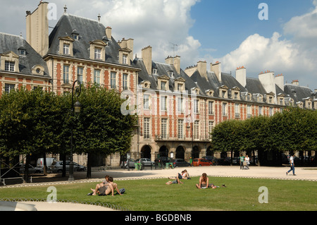 Persone o turisti che si rilassano sul prato della Piazza Centrale o Parco di Place des Vosges, Piazza della Città o Piazza della Città, Parigi, Francia Foto Stock