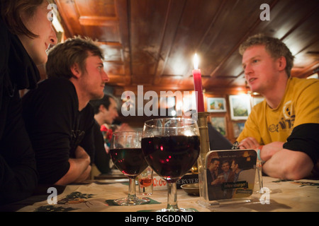 Giovani sat di bere vino rosso intorno a un tavolo in 'La metropolitana' apres ski bar in St Anton am Arlberg, Austria, l'Europa. Foto Stock
