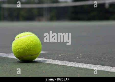 Un primo piano di un giallo palla da tennis appena al di fuori della linea di base su un asfalto campo da tennis. Foto Stock