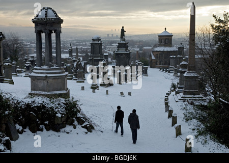 Due persone a piedi attraverso la necropoli di Glasgow sotto la neve in inverno 2009 Foto Stock