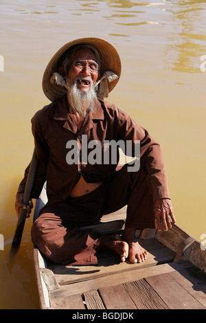 Anziani, pescatore sorridente nella sua barca nel porto di Hoi An, Vietnam, sud-est asiatico Foto Stock