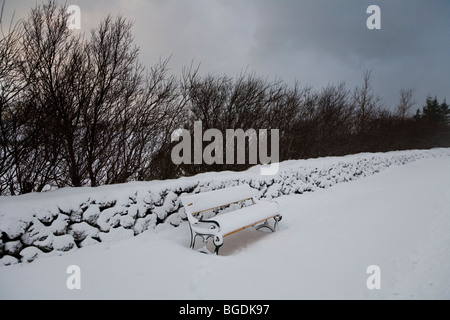 La neve su un banco in un parco pubblico. Hafnarfjordur, una maggiore area di Reykjavik, Islanda. Foto Stock