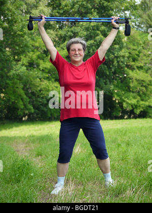 Senior donna facendo una serie di warm-up con esercizi di poli a piedi Foto Stock