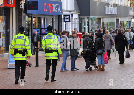 Due poliziotti di pattuglia nella trafficata shopping high street Foto Stock