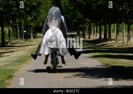 Foto di stock di una sposa e lo sposo su una bicicletta in tandem con le parole appena sposato incollata sul retro del ciclo. Foto Stock