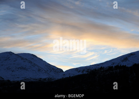 The sun setting behind snow covered mountains in Norway, winter Foto Stock