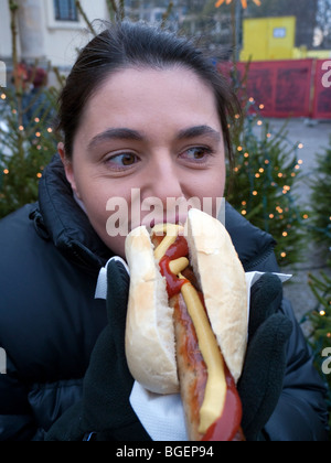 Donna di mangiare una grande bratwurst salsiccia con pane a Berlino Germania Foto Stock