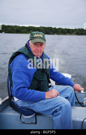 Senior anziani condito guida di pesca la guida alumnacraft barca da pesca nel freddo umido meteo instabile acqua onde wake azione Foto Stock
