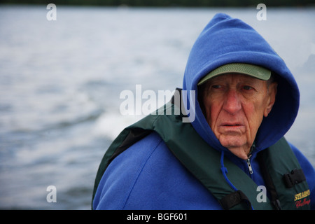 Senior anziani condito guida di pesca la guida alumnacraft barca da pesca nel freddo umido meteo instabile acqua onde wake azione Foto Stock