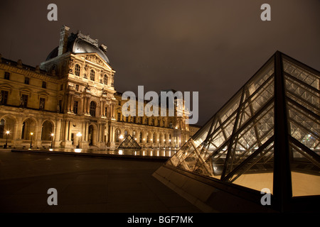 Il museo del Louvre e la piramide triangolare illuminata di notte Foto Stock