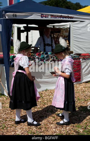 Due ragazze cercando nel loro abbigliamento tradizionale in piedi al di fuori del negozio in Baviera, Germania Foto Stock