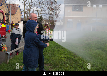 Un bambino ha un andare con una lotta antincendio tubo flessibile per acqua a Londra Vigili del Fuoco la consapevolezza della sicurezza giorno a Feltham, Londra, Regno Unito. Foto Stock