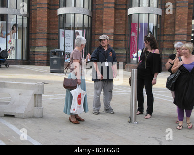 Collettore di carità per la cura, chugger, accosts pubblico in Leeds shopping centre Foto Stock