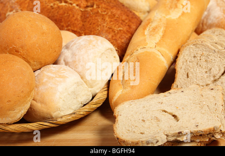 Un granaio con i rotoli su una breadboard con affettato e unsliced pani. Foto Stock