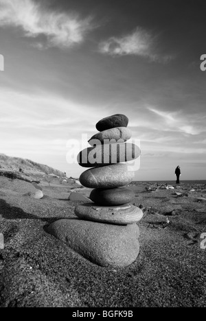 Una torre in pietra costruito sulla spiaggia al punto di disprezzare il vecchio faro visibile in background Foto Stock