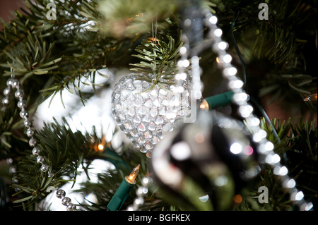 Un colorato a forma di cuore decorazioni ninnolo splendidamente collocato su un pino albero di Natale in un soggiorno finestra di baia in dicembre. Foto Stock