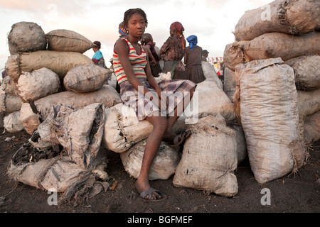 Una ragazza seduta sui sacchi di carbone al porto di Gonaives, dipartimento di Artibonite, Haiti Foto Stock