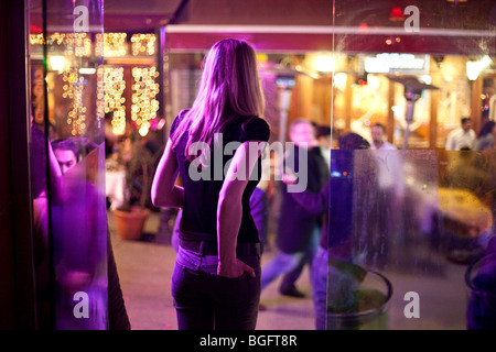 Una donna bionda sta al di fuori di un bar club nel quartiere alla moda di quartiere Taksim di Istanbul, Turchia Foto Stock