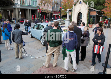 La folla raccolta di controllare la Nissan Leaf, auto elettrica sul display. Foto Stock