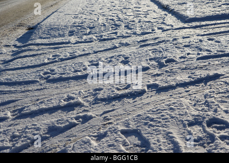 Footprint e pneumatici vettura lasciando segni di una unità nella neve su un sentiero nel Regno Unito Foto Stock