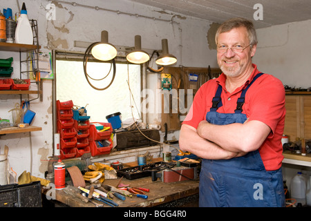 Sorridente e felice senior artigiano nel suo garage Foto Stock