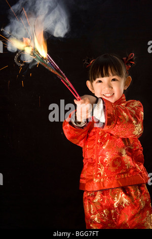 Ragazza in abiti Cinesi tradizionali la riproduzione di fuochi d'artificio Foto Stock